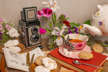 cup of tea with cookies, flowers, and vintage film camera