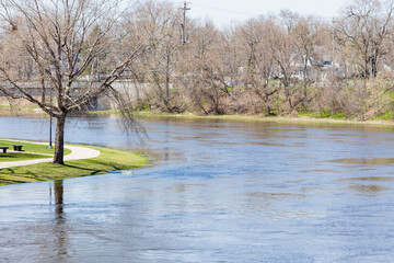 A river at flood stage and a walkway in a park in the early spring.