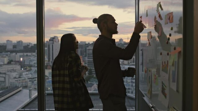 Colleagues silhouette working sticker wall evening close up. Startupers planning