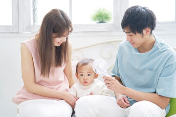 Obraz premium 家で赤ちゃんにポータブル扇風機を使う父親