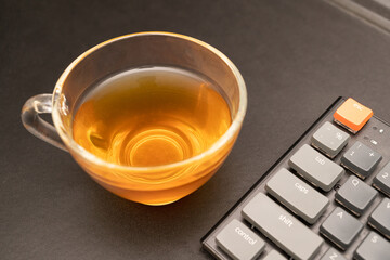 Glass cup of hot ginger tea on the black desk.