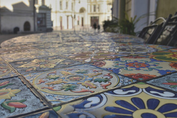 Wet surface of a colorful mosaic table with raindrops in a street cafe against the backdrop of an abstract cityscape.