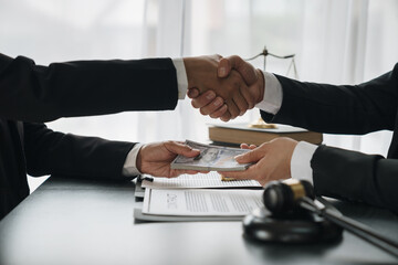 Businesswoman, investor shaking hands and giving bribe to lawyer to help win court case with documents to sign agreement The concept of bribery and money delivery on the table. Fraud