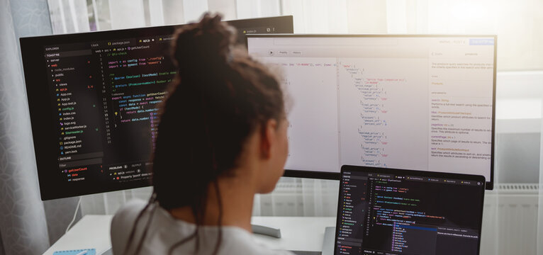 Back view of woman coding on computer, professional female programmer working in room