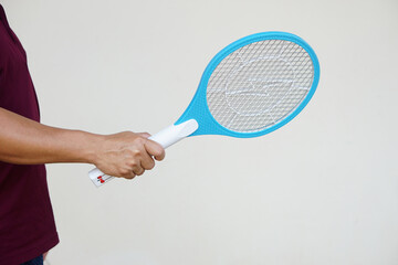 Closeup hand holds mosquito electric swatter racket. Concept, electric device to kill mosquitoes, insects, bugs by swatting to flying insects that can cause disease or annoyed feeling.      