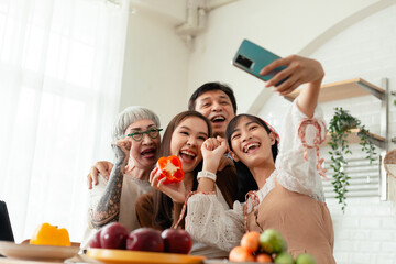 happy family Asian family taking selfies with smartphones together cooking food in the kitchen. spending time together cook together in the kitchen and dine together happily