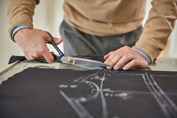 원단가위로 밑그림을 따라 원단을 자르는 디자이너의 손