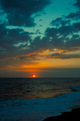 Sunset on black sand beach in Guatemala, tropical sunset full of color and waves.