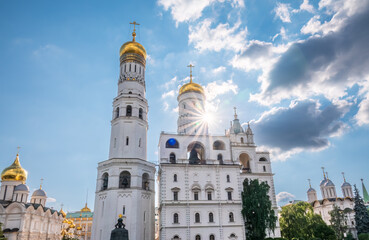 Fototapeta na wymiar Ivan the Great Bell Tower, with Assumption Belfry on the right in Moscow Kremlin. Blue sky background with sunbeams