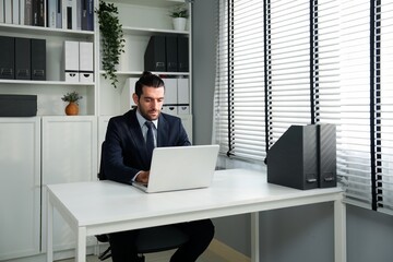 Caucasian handsome employee man working overtime and use laptop for meeting online with financial team in the office