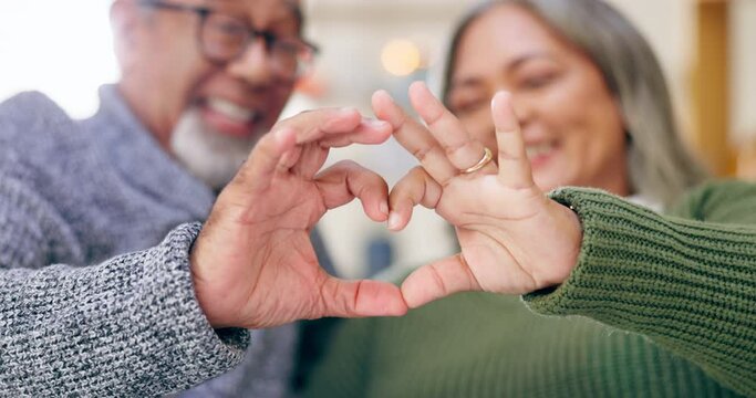 Heart, hands and couple in home for love, kindness and commitment to life partner, relationship and sign. Closeup man, happy woman and finger shape of care, support and trust of hope, peace and emoji