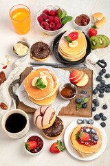 Pancakes with fresh fruits, donuts and coffee on a white background.