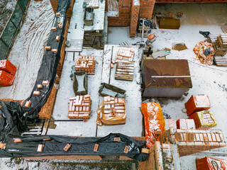 Top view of the construction site. Construction of a red brick house. Building in winter. Detailed shot of the construction site. Snow on the construction site.