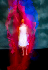 Mystical, blurry dance photo of adult woman with colorful fabric.