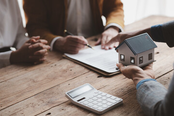 A home rental company employee is handing the house keys to a customer who has agreed to sign a rental contract, explaining the details and terms of the rental. Home and real estate rental ideas. - obrazy, fototapety, plakaty