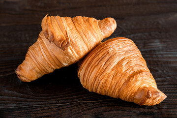 Two croissants on a wooden cutting board. Rustic dark table. Food banner. Tasty fresh croissant, jam, orange juice. Continental breakfast served with freshly baked pastry. Close up view, Good morning