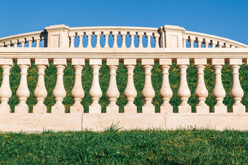 Fototapeta na wymiar Beautiful marble railings in a landscaped park against a blue sky