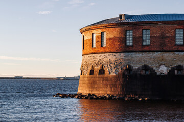 An old fort on the shore of the bay illuminated by the rays of the setting sun