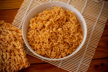 Instant noodles in white bowl on wooden background. Quick cup, Fast food concept.