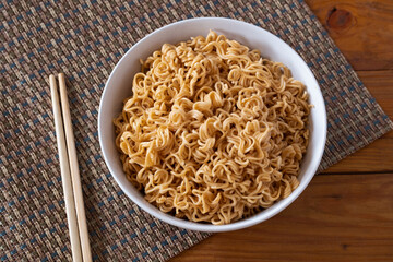 Instant noodles in white bowl on wooden background. Quick cup, Fast food concept.