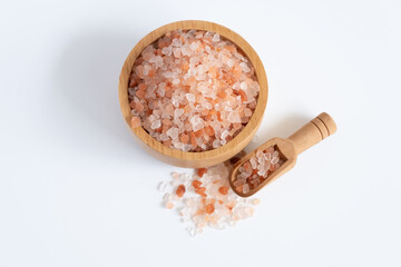 Top view of Himalayan pink rock salt in wooden bowl and scoop isolated on white background.