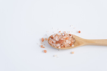 Himalayan pink salt (rock salt, halite mined) in wooden spoon isolated on white background.