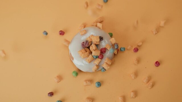 Decorating fresh white glazed donut with sweet colourful sweets, top down view