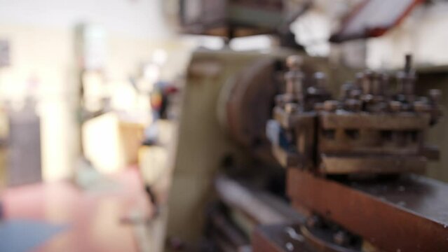 Slider shot of a metal turning lathe. Framing moves from the chuck, spindle and head stock to the tool post. Iron or steel metal shavings are visible. Shot in Stornoway on the Isle of Lewis, Hebrides.