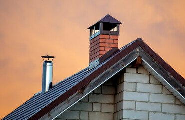 The roof of the house against the background of the sunset