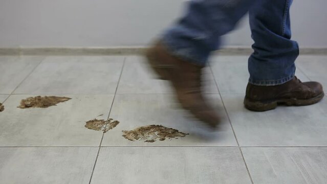 A man in dirty shoes walks on a clean floor. A man tramples in dirty shoes on the ceramic floor.