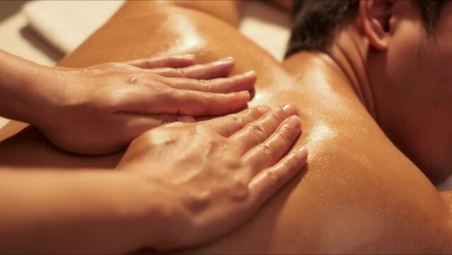 Top view, Hand of masseuse doing massage back with aromatherapy oil on back of a man customer in spa salon.