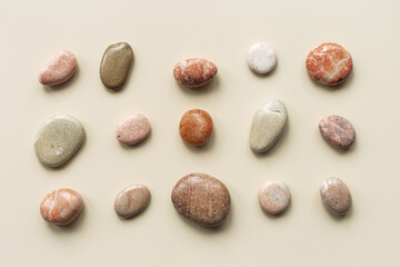 Aesthetic minimal pattern with set of sea pebble stones on beige background. Square composition from natural round smooth stone neutral color. Collection of rocks, summer concept, top view © yrabota