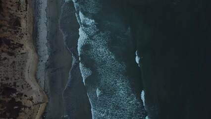 Cenit view from a drone flying over the beach showing the sea and the edge of a cliff