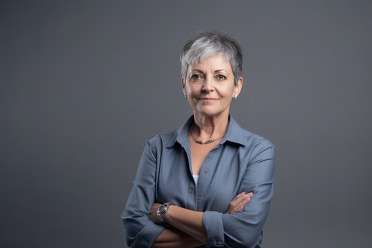 Senior woman confident, arms folded, thoughtful smile, grey background, copy space. Photo generative AI