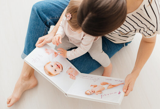 mother and daughter watch photobook from discharge of newborn baby.family tradition of printing photos and looking at them with children and remembering.