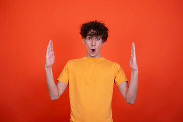Young attractive guy and men's health problems. Emotional man. Orange background.