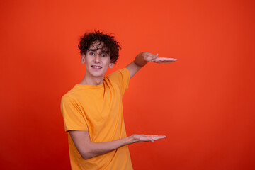 Young attractive guy and men's health problems. Emotional man. Orange background.