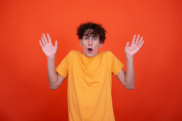 Young attractive guy posing in the studio. Emotional man. Orange background.