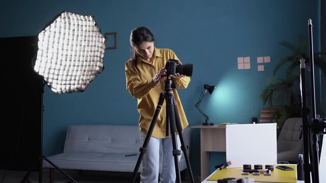 Female photographer setting up camera in home studio. Professional photographer on fashion shoot in photo studio with lighting equipment