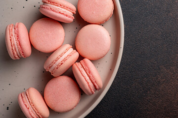 Pink macaroons on a plate on a dark table
