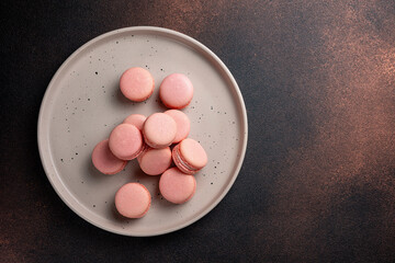 Pink macaroons on a plate on a dark table
