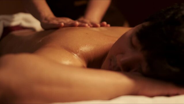 Selective focus, Hand of masseuse doing massage back with aromatherapy oil on back of a man customer in spa salon.