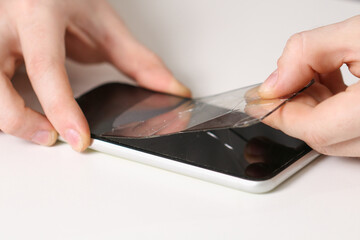 man removes old cracked protective glass from phone. Broken glass