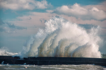    Huge wave crashing on the pier on a sunny stormy day
