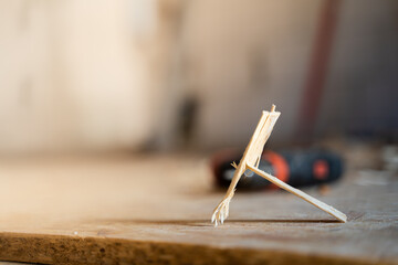 A wooden fragment lies close-up against the background of construction tools on a blurred background. Small piece of wood waste. Precise fitting of wooden parts