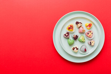 Plate with different chocolate on colored background. Assortment of fine chocolates top view vith copy space Health and obesity concept