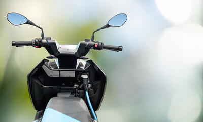 Electric scooter with connected charging cable on a green background  © scharfsinn86