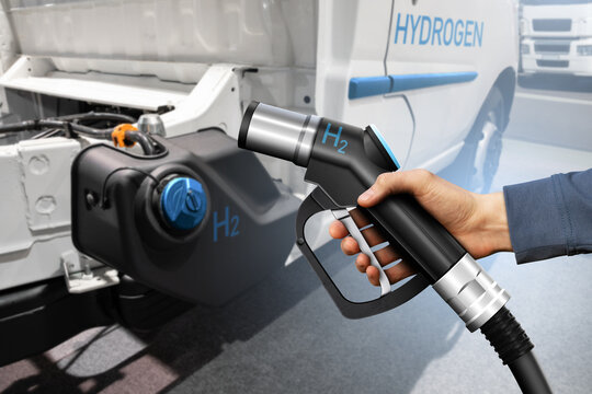 Hand with H2 fueling nozzle on a background of hydrogen fuel cell truck. Eco-friendly commercial vehicle concept	