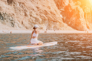 Woman sup yoga. Happy sporty woman practising yoga pilates on paddle sup surfboard. Female stretching doing workout on sea water. Modern individual female hipster outdoor summer sport activity.