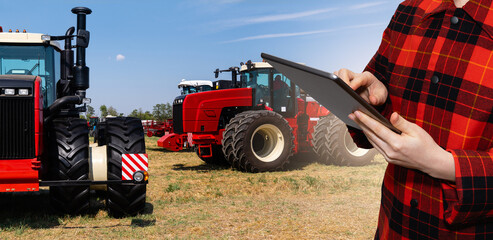 Farmer with a digital tablet on the background of an agricultural tractor	